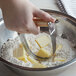 A hand holding a Fox Run Wire Pastry Blender mixing butter and flour.