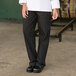 A person wearing Uncommon Chef red and white pinstripe chef pants with a white shirt.