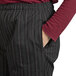 A woman wearing red and white pinstripe chef pants with her hands in her pockets.