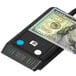 A Dri Mark FlashTest counterfeit bill detector on a counter with a paper bill in it.
