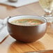 An Acopa Embers hickory brown stoneware bowl filled with soup on a table.