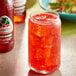 A glass of Jarritos Strawberry Soda with ice on a table in a Mexican restaurant.