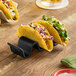 A Tablecraft black taco taxi holding three tacos on a table.
