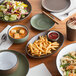 Acopa Hickory Brown Matte Coupe Stoneware Plates on a table with plates of food and drinks.