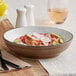 An Acopa Embers hickory brown stoneware bowl filled with food on a table.