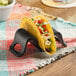 A black Tablecraft taco holder with a taco in it on a table.