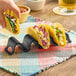A hand holding a Tablecraft black taco holder with 3 or 4 tacos in it.