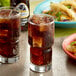 A glass of Jarritos Mexican Cola with ice and a taco on a plate.