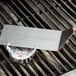 A person using a Cooper-Atkins grill thermometer on a grill.