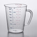 A Carlisle clear polycarbonate measuring cup with red and blue numbers and a handle.