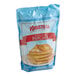 A blue and white bag of Krusteaz Sweet Cream Pancake Mix on a white background.