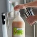 A person pouring I. Rice banana milkshake base syrup into a container.