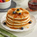 A stack of Krusteaz buttermilk pancakes with blueberries and syrup.