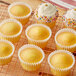 A group of Krusteaz yellow cupcakes with frosting and sprinkles on a cooling rack.