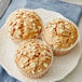 A plate of three Krusteaz Oat Bran muffins with oat flakes on top.