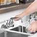 A person pouring water into a sink using a Waterloo Replacement Ceramic Faucet Cartridge Repair Kit with hot handle.