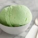 A close-up of a white bowl of green I. Rice sour apple ice base.