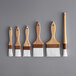 A row of five wooden pastry and basting brushes with brown handles.