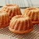 Three baked bundt cakes on a cooling rack.