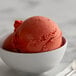 A bowl of I. Rice Strawberry Kiwi Water Ice on a white background with a spoon.