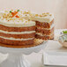 A Krusteaz carrot cake with a slice missing on a white stand.