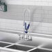 A white wall-mounted pre-rinse faucet with an 8" center and hose.