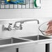 A person using a Waterloo wall-mounted faucet to wash a bowl in a sink.