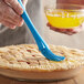 a blue pastry brush being used to decorate a pie