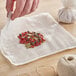 A hand using Monarch Brands bleached cheesecloth to make a tea bag with spices.