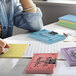 A person writing on a stack of Oxford assorted color ruled index cards.