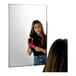 A woman brushing her hair in front of a Bobrick wall-mounted mirror.