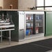 An Avantco stainless steel back bar refrigerator with sliding glass doors filled with drinks.