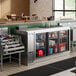 An Avantco back bar cooler with drinks on a metal shelf.