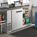 A woman taking a container of food from an Avantco back bar refrigerator.