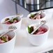 A tray of small white bowls with food on them and a Front of the House stainless steel cocktail fork.