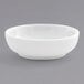 A Front of the House bright white porcelain ramekin on a gray surface.