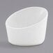 A white slanted porcelain sauce cup on a gray background.
