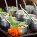 A tray of silver bowls with silver demitasse spoons on a table.