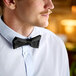 A man wearing a Henry Segal black clip-on bow tie over a white shirt.