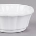 A white Carlisle scalloped ramekin on a gray surface.