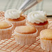 A close-up of a Krusteaz lemon cupcake in a paper wrapper with frosting on top.