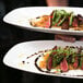 Two white Front of the House rectangular porcelain platters with food on them.