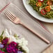 An Acopa Phoenix rose gold stainless steel dinner fork on a plate of food.