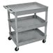 A Luxor gray plastic utility cart with three shelves and wheels.