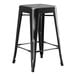 A Lancaster Table & Seating black metal backless outdoor counter height stool.