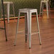 Lancaster Table & Seating silver backless barstools in a room.
