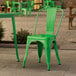 A Lancaster Table & Seating Jade Green metal chair on a stone patio.