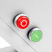 A white surface with a green and silver button and a red and silver button.