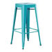 A turquoise metal Lancaster Table & Seating outdoor backless barstool.