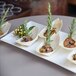 A rectangular white porcelain plate with shrimp and rosemary sprigs on it.